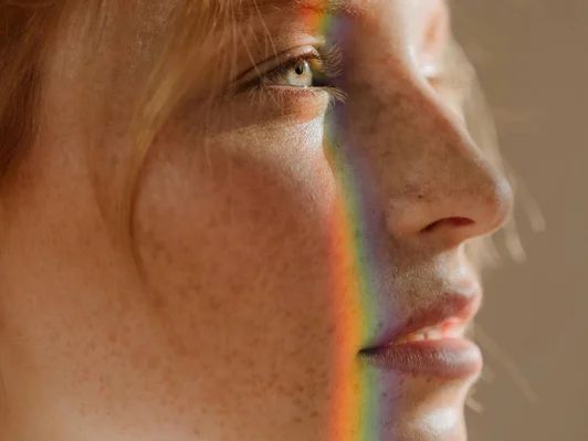 Perfil de una mujer con un reflejo de luz de colores en la cara