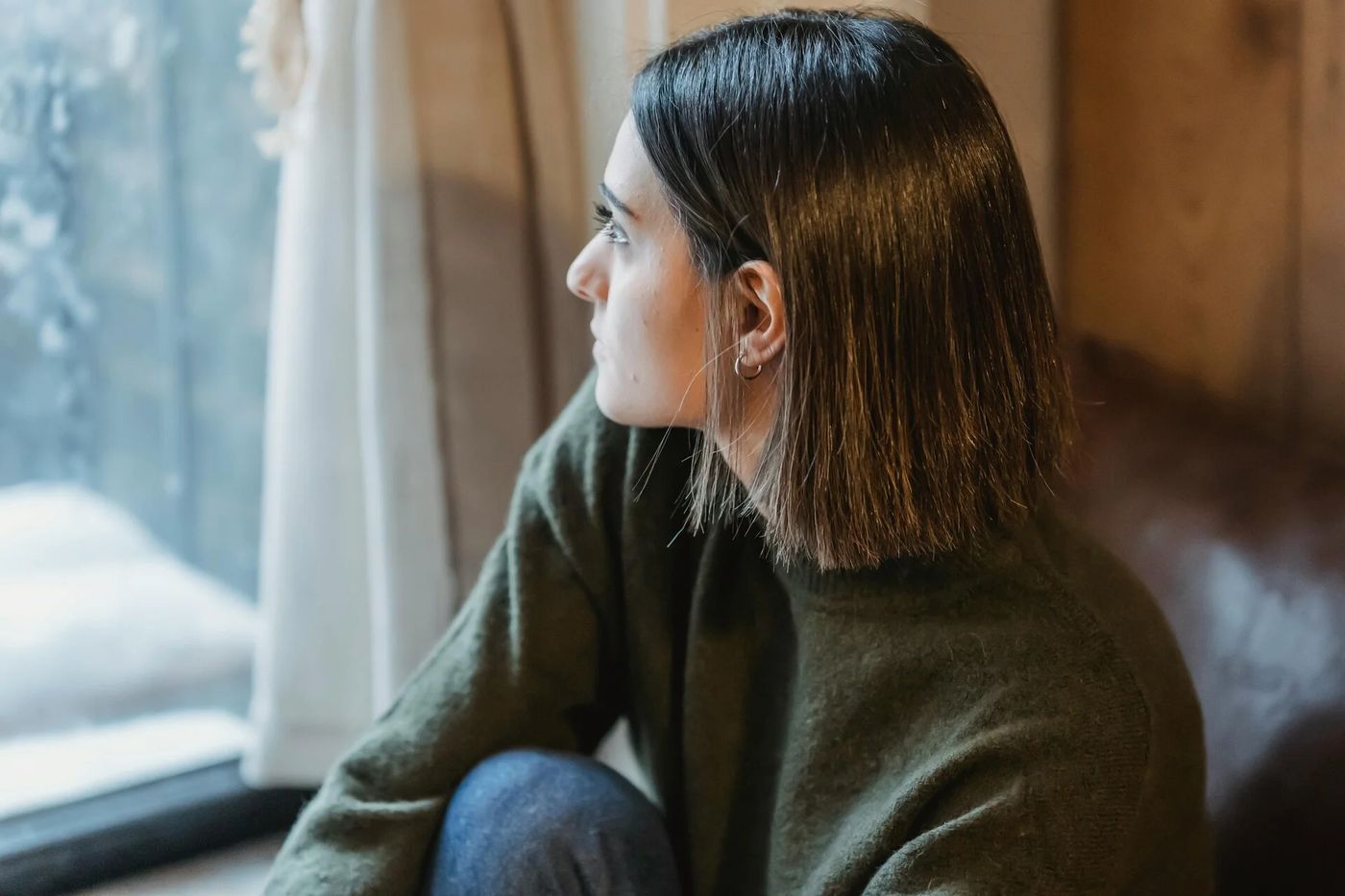 Mujer mirando por la ventana, pensativa